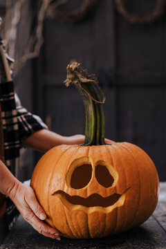 A woman carving a pumpkin for a halloween party decoration in October.