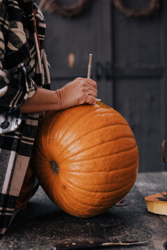A woman carving a pumpkin for a halloween party decoration in October.