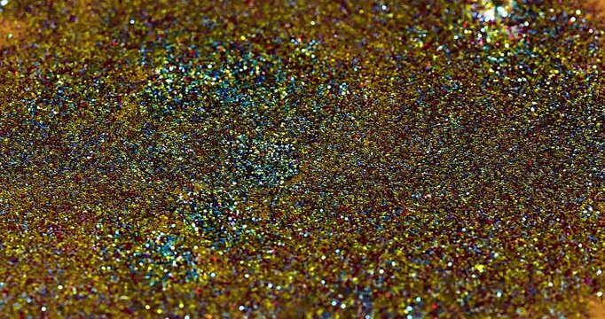 Gocce di emulsione con polvere di glitter colorata che cadono al rallentatore in una soluzione di acqua e glitter