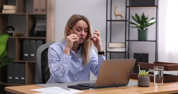 Woman feeling fatigue while working with laptop at wooden desk in office