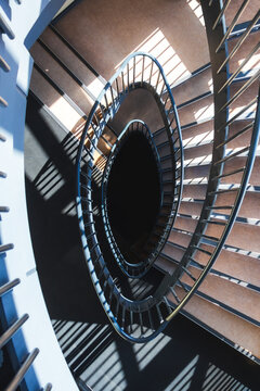 Architectural spiral staircase view from above with dramatic light and shadows