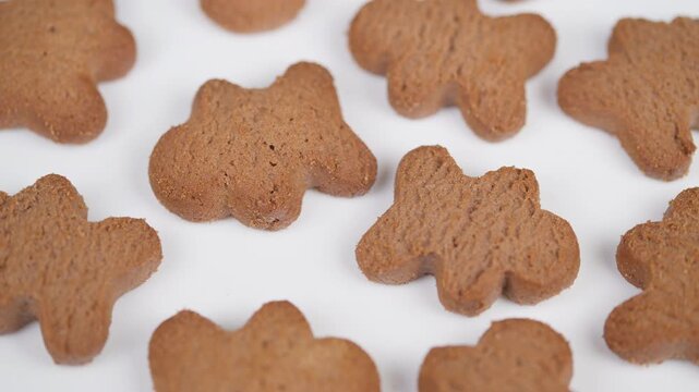 Festive cookies on plain background. Closeup of baked gingerbread treats with warm lighting. Detailed view of holiday gingerbread pastries arranged in repeating pattern