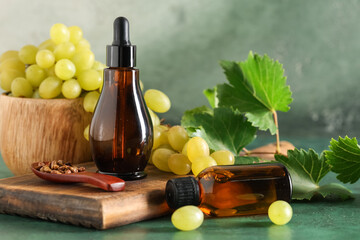 Bottles of cosmetic grape seed oil on green background