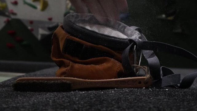 A video of someone grabbing a bit of chalk, getting ready to go bouldering.