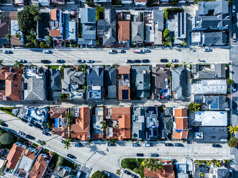 Top down aerial view of dense coastal residential blocks with tiled rooftops and palm lined streets in Long Beach California