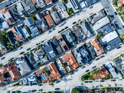 Top down aerial view of dense coastal residential blocks with tiled rooftops and palm lined streets in Long Beach California