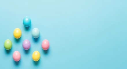 Assortment of brightly colored Easter eggs arranged neatly in a pyramid shape on a solid pastel blue background creating ample copy space for spring designs