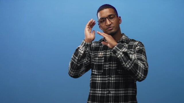 Young black man rests hands against cheek with closed eyes in studio, making a sleeping gesture; calm rest.