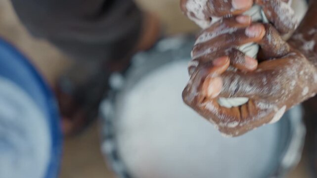 Black bucket hands washing cloth soap intimate overhead shot of sudsy palms scrubbing garment beside waterfilled pails, candid house chores in modest outdoor yard, focused texture, slow motion detail,