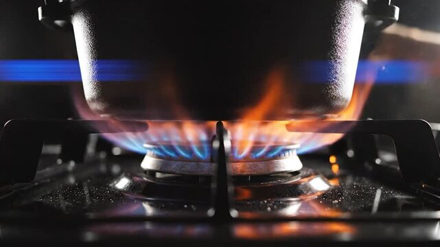 Gas stove burner with cooking pot and bright blue flame generating sparks