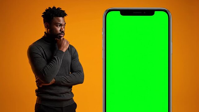 Man thinking next to green screen phone.