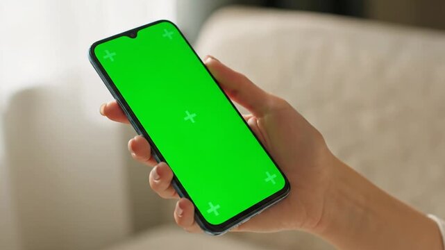Hand holding green screen phone with mockup.