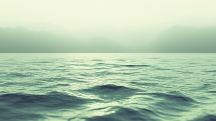 Fototapeta premium Gentle waves form on the serene sea surface under a soft, hazy sky, evoking tranquility and vastness.
