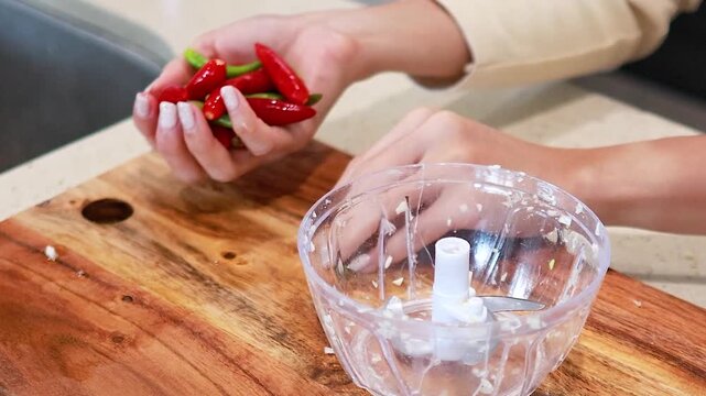 Hands Placing Fresh Chili Peppers into a Manual Food Chopper