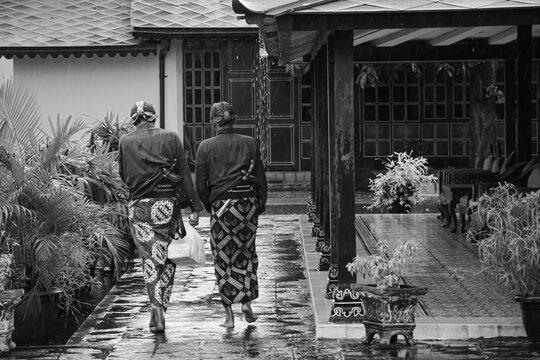 Black and whihte portrait of two King&rsquo;s servant called Abdi Dalem who wearing traditional Javanese clothes walking toward the aisle 