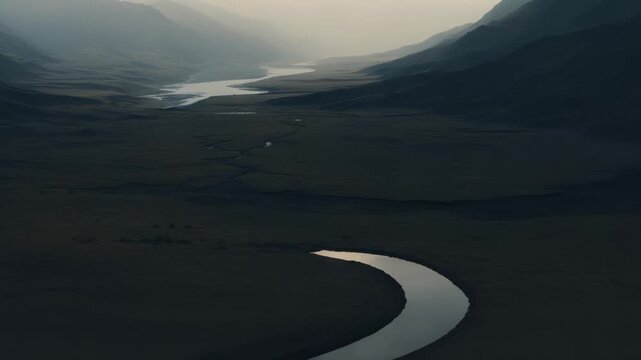 Ethereal atmosphere covering a vast wilderness landscape, with misty mountains enveloping a tranquil river flowing through a desolate grassland valley under an overcast sky