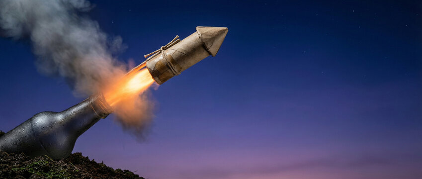 Bottle rocket launching with fiery trail into twilight sky for Bastille Day fireworks. Patriotic display of pyrotechnics celebrating French national holiday and independence. Explosive celebration