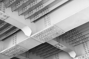 Close-up view of the underside of a white painted steel bridge, featuring riveted girders, repeating ribs, and structural spans. Ideal for architecture, engineering, infrastructure, and industry