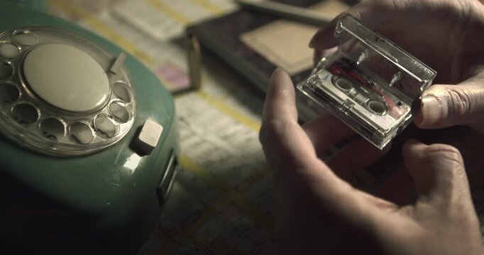 Person inspects small recorder tape close up on retro crime desk Ideal for detective, cold case, investigation, vintage, 1970s, crime scene, planning, conspiracy, noir_