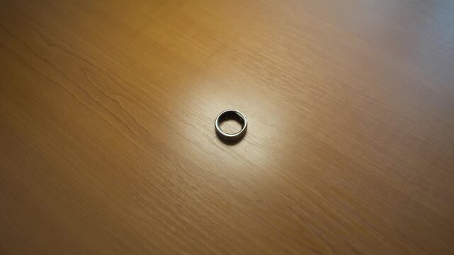 A smart silver ring lies on the table, flashing different colors. Modern technology that supports health and monitoring.