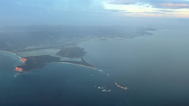 Aerial Left side view take from an airplane cockpit of Ibiza island, city and airport while flyingb through a layer of ethereal clouds.