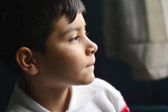 Profile of calm latin boy in the dark room.