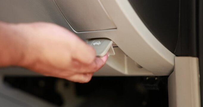 Close up of a male hand pulling the hood release lever inside a car to open the engine compartment. Driver checking vehicle before a road trip or doing auto maintenance. High quality 4K video.