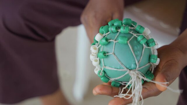 Green toy shared softly between hands. Gentle hands pass quiet green rattle amidst closeness. Softly passing green toy between caring hands during moment of intimate closeness and tenderness