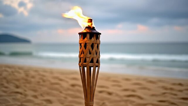 Flaming tiki torch on sandy beach at tropical evening
