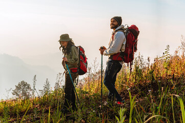 Two people are hiking up a hill, one of them wearing a green hat