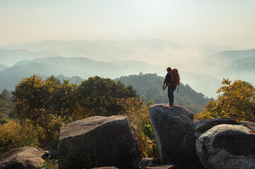 man is standing on a rock in the mountains with a backpack