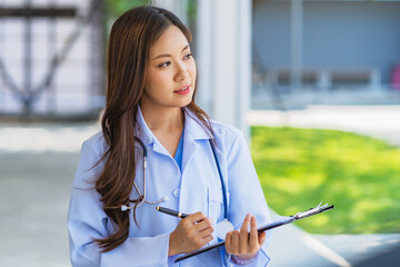 woman in a white lab coat is writing on a clipboard