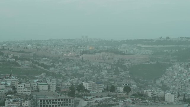 Cinematic view of the historic Old City walls, the Dome of the Rock, and the Temple Mount in Jerusalem. A look at the holy site sacred to Judaism and Islam, captured during a hazy day with low visibil