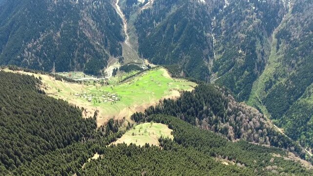 Aerial view of lush green meadow within forest glade on Black Sea mountain highlands. Scenic grassy clearings and dense woodland spread across steep hills above deep valleys.