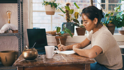 Laptop screen, entrepreneur or woman writing in notebook, small business plan or track pottery sales. Store admin, to do list or person with budget journal to monitor expenses, ceramic startup or pc © peopleimages.com