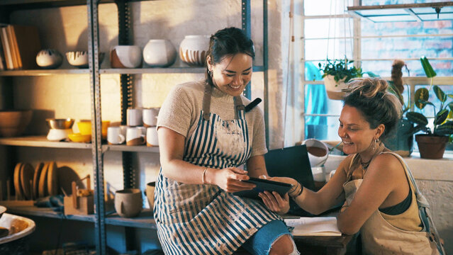 Reading, ceramic or team in store with tablet, creative insight or customer review in clay shop. Partnership, women or owners with tech, consumer feedback or design planning in pottery business.