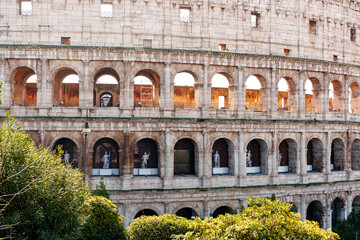 Fototapeta premium Visitors explore the Colosseum in Rome during the daytime with sculptures in view