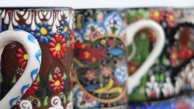 Row of traditional turkish souvenir ceramic mugs with colorful patterns on display for sale in a gift shop