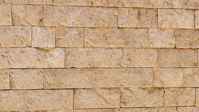 A rustic garden wall featuring textured sandstone blocks in warm beige tones, arranged in a neat horizontal pattern that perfectly complements natural outdoor landscapes and architecture
