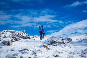 A young woman walking in the snow with a backpack