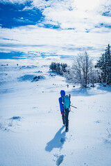 A young woman walking in the snow with a backpack