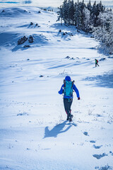 A young woman walking in the snow with a backpack