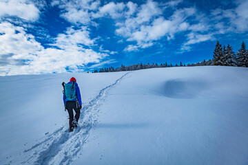 A young woman walking in the snow with a backpack