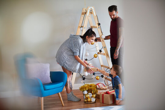 Modern family at home at Christmas time using ladder as Christmas tree