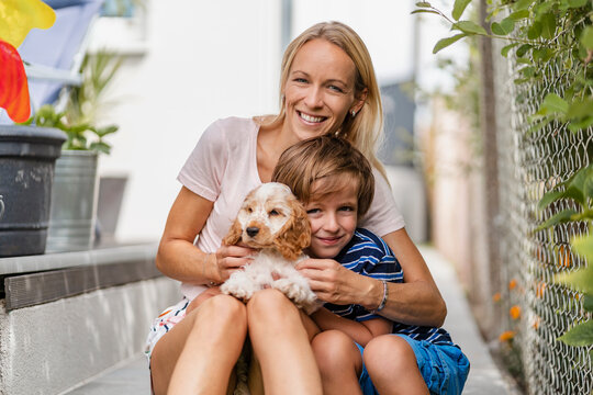Portrait of mother snd son cuddling with cute dog puppy