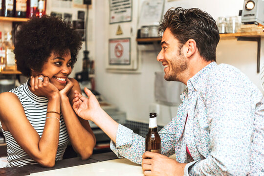 Man holding beer bottle touching female bartender while flirting with her at bar counter
