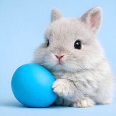 Obraz premium Adorable white fluffy bunny holding blue easter egg on pastel background cute animal portrait