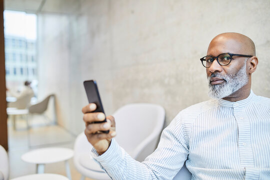 Portrait of bald mature businessman with cell phone