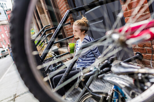 USA, New York City, woman sitting on stoop drinking a smoothie in Manhattan