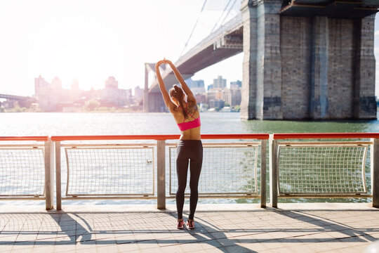 Woman doing stretching exercises in Manhattan near Brooklyn Bridge in the morning